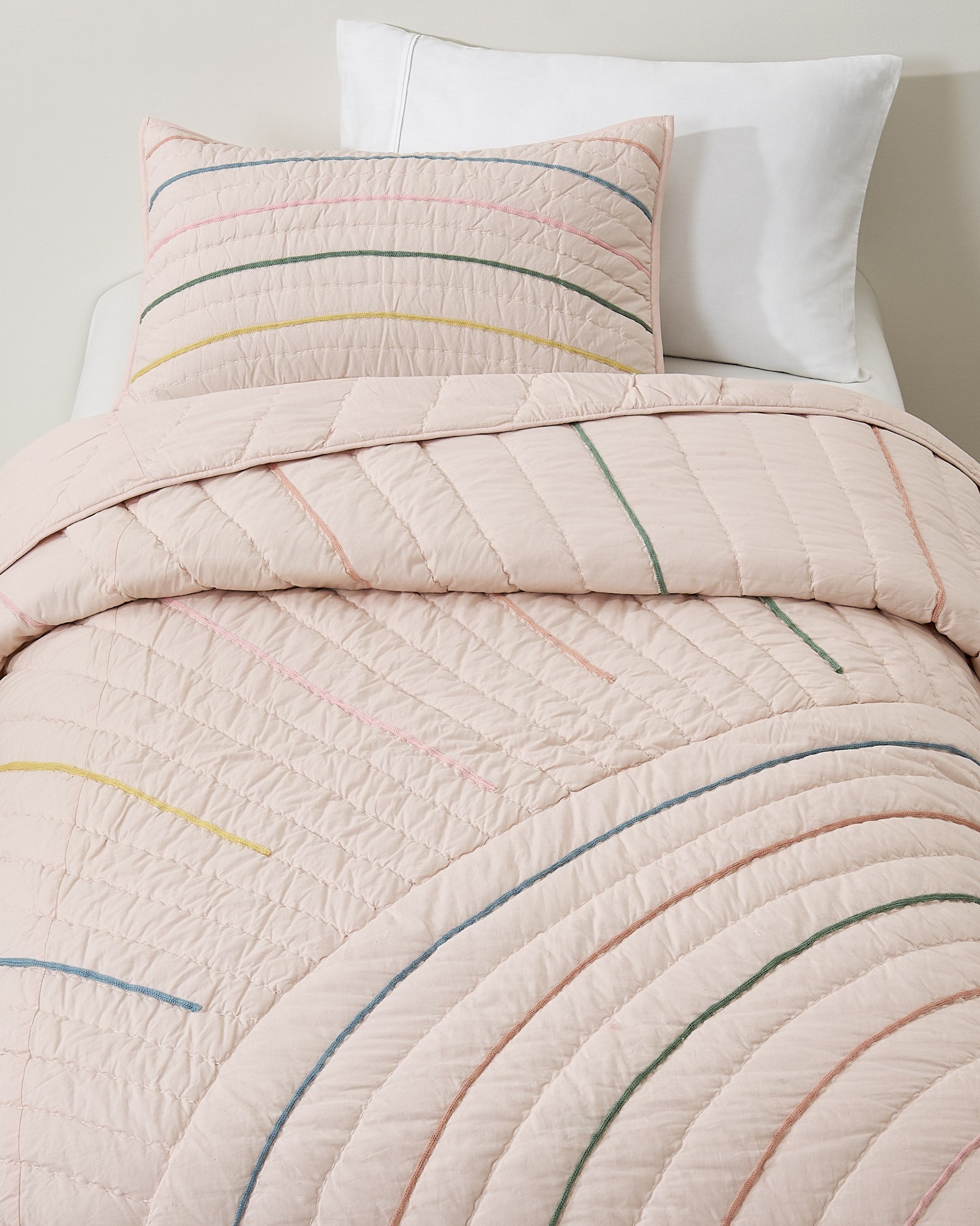 Hush Rainbow kids AC quilt on a bed