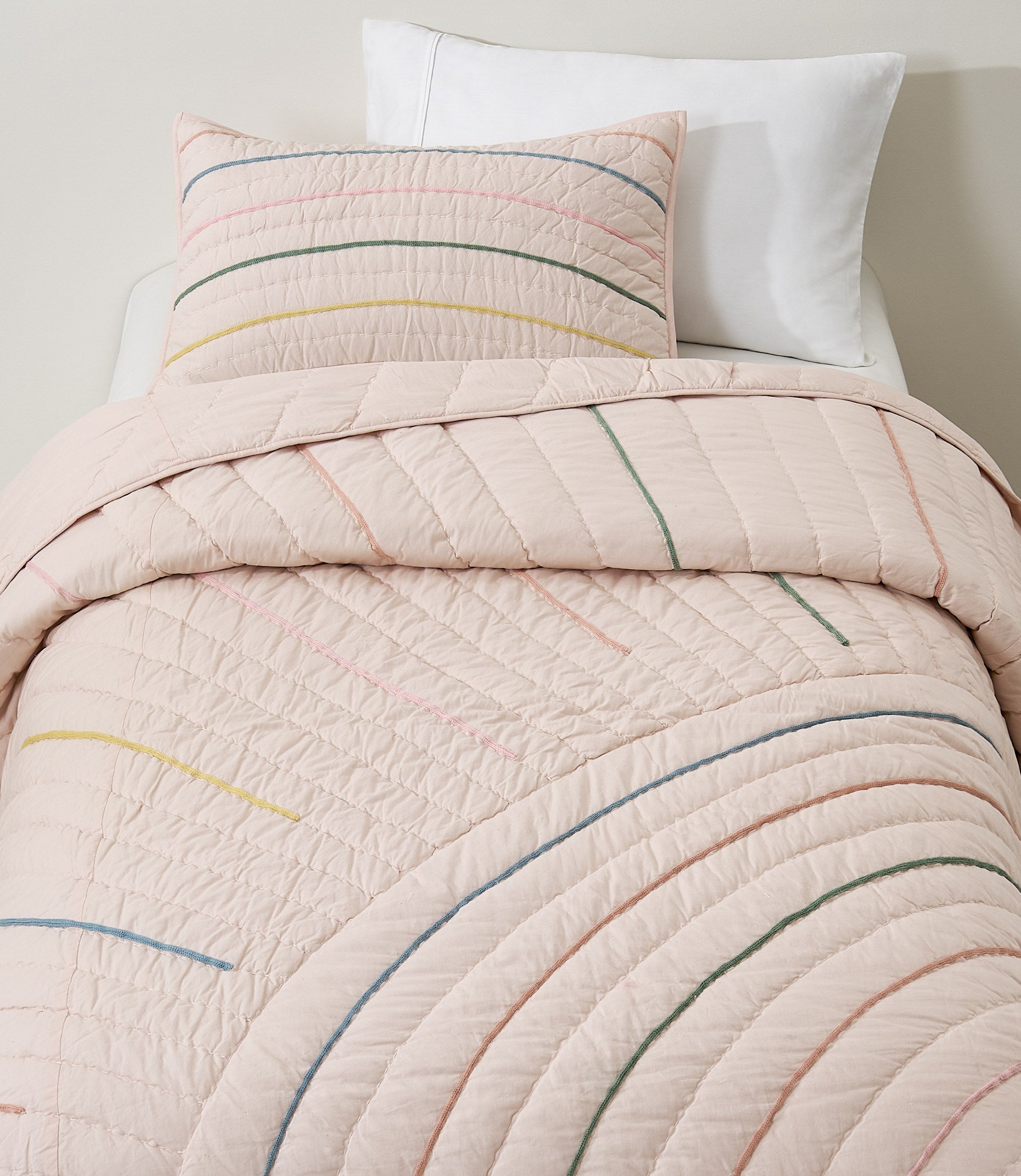 Hush Rainbow kids AC quilt on a bed
