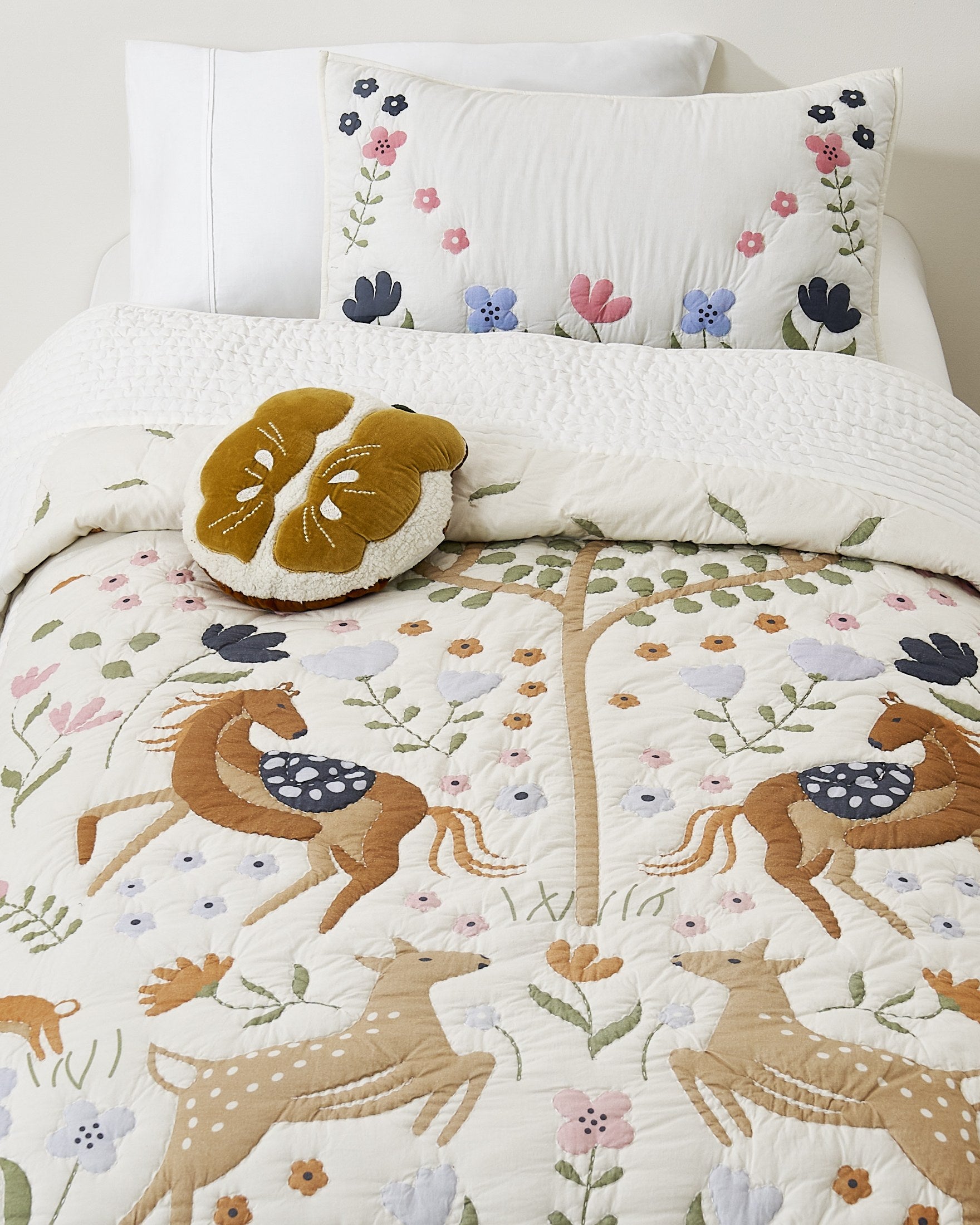 Tiny Meadow kids AC quilt on a bed