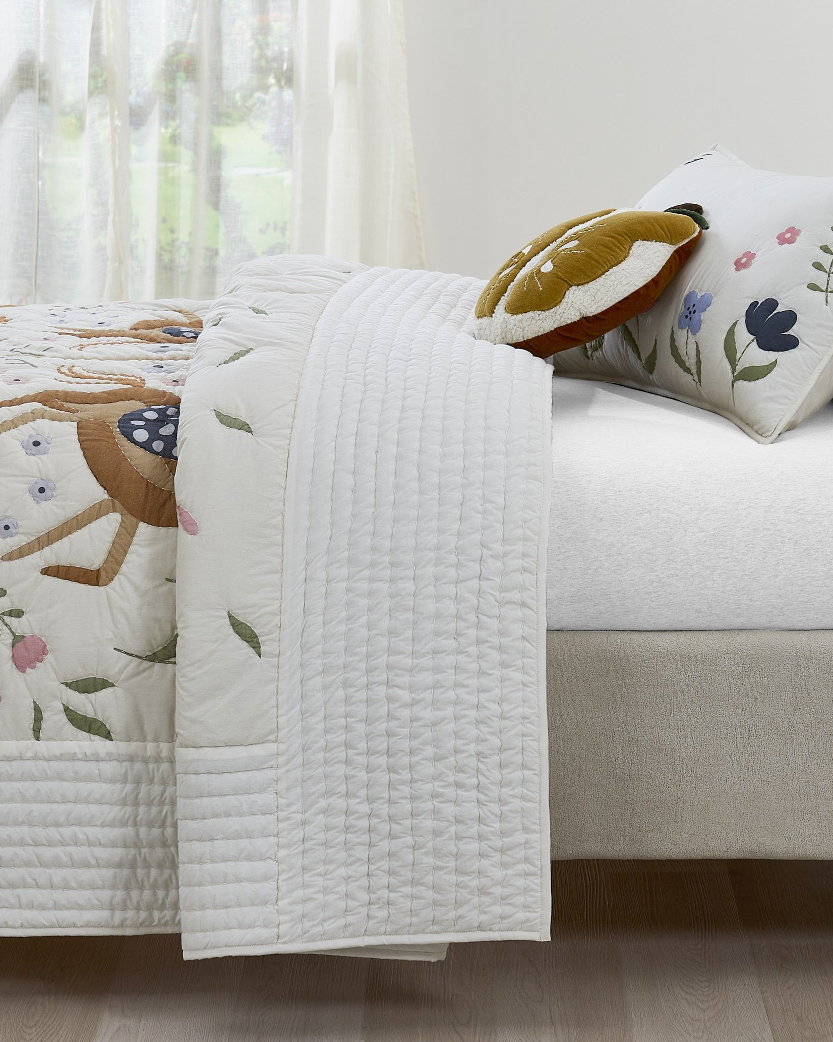 Tiny Meadow kids AC quilt styled in a bedroom