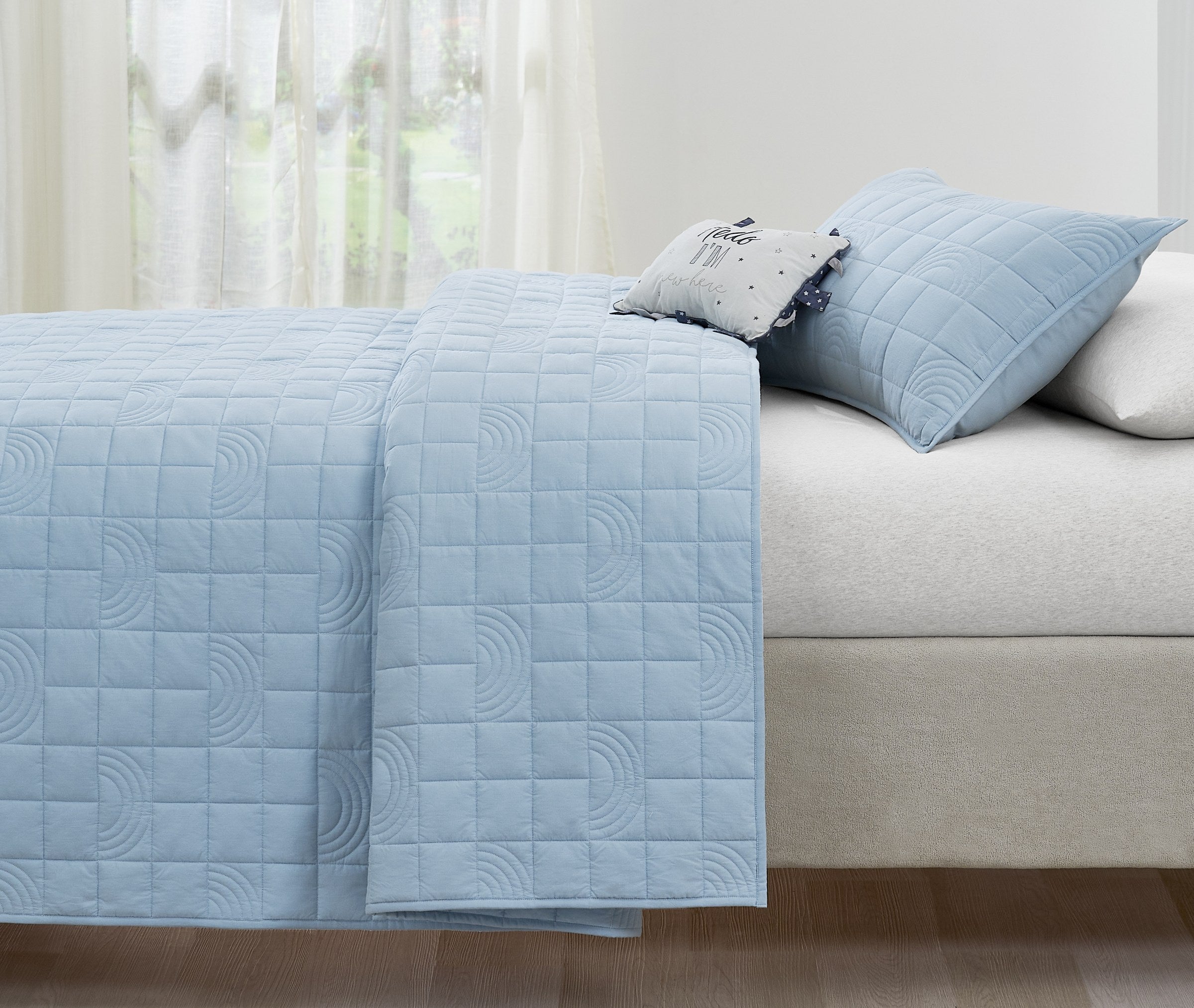 Blue Rainbow kids AC quilt styled in a bedroom
