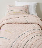Hush Rainbow kids AC quilt on a bed