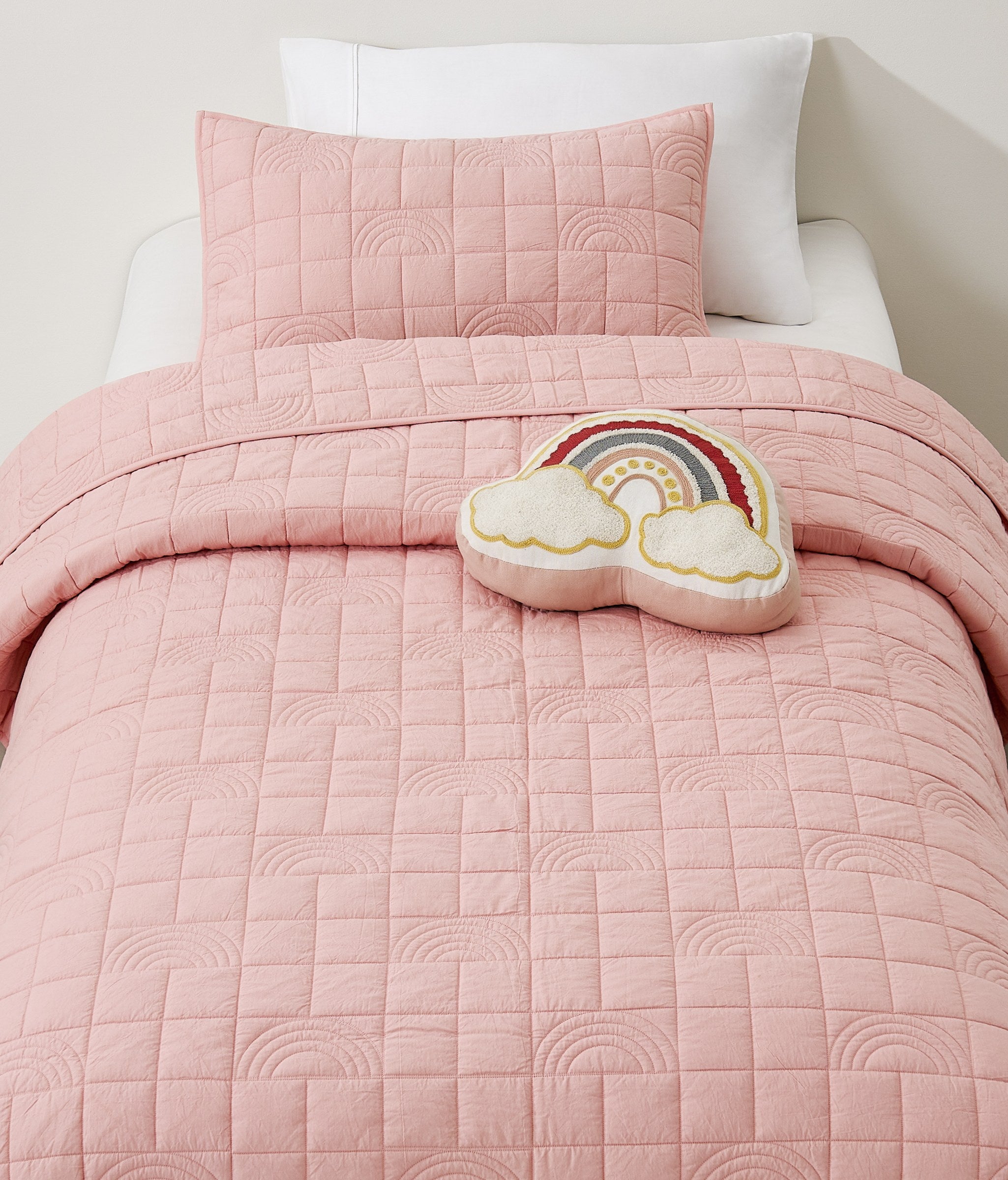 Pink Rainbow kids AC quilt on a bed