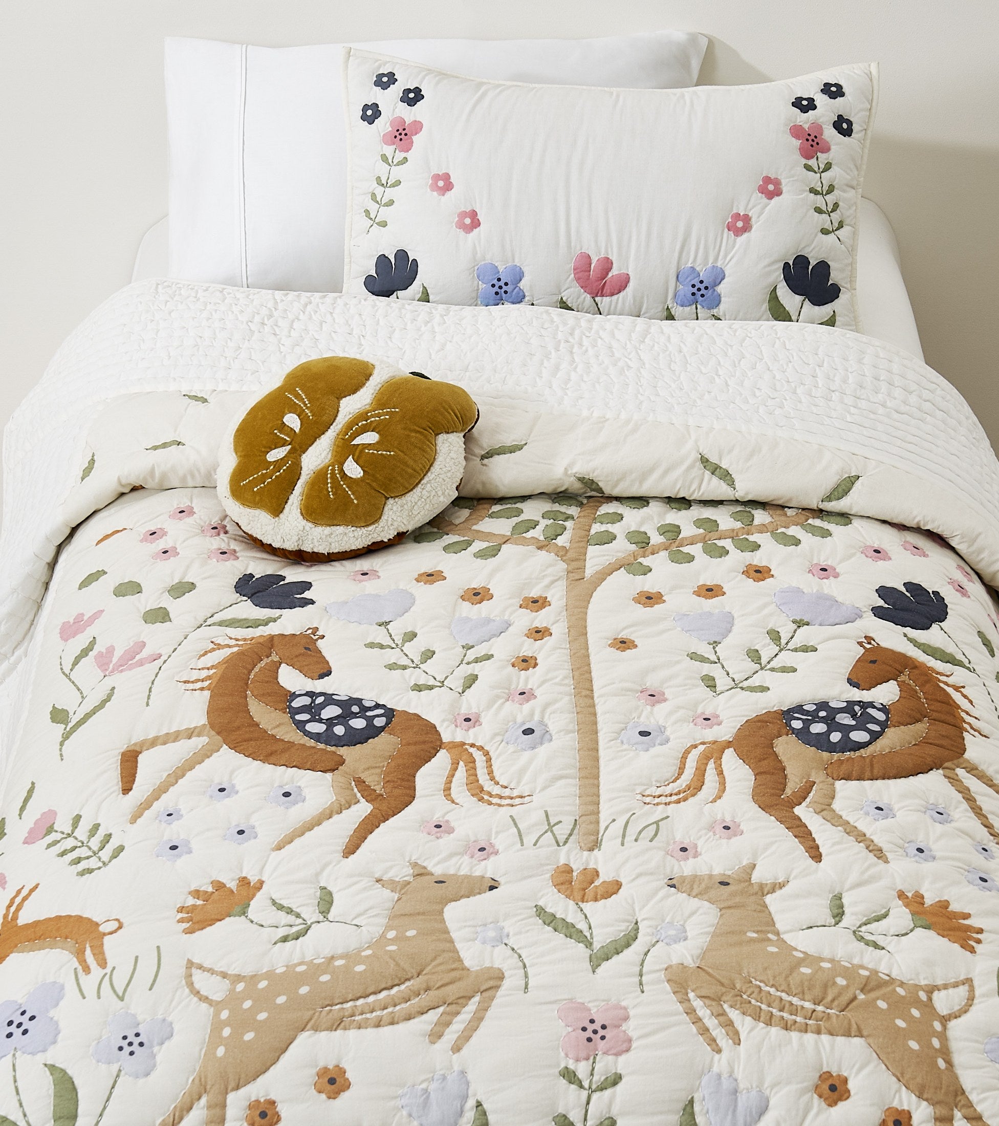 Tiny Meadow kids AC quilt on a bed