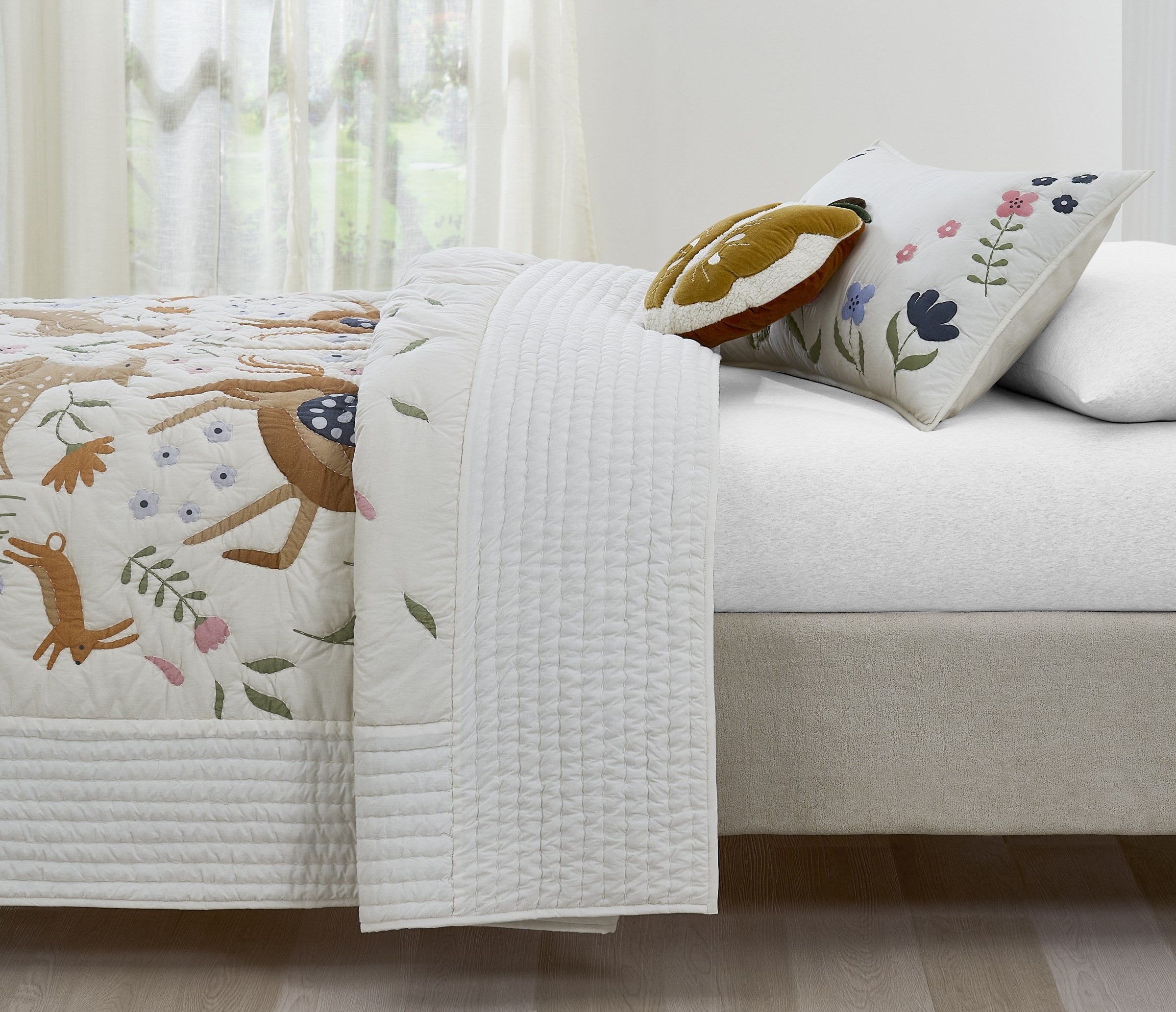 Tiny Meadow kids AC quilt styled in a bedroom